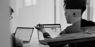 Male office worker with macbook laptops in meeting room via unsplash